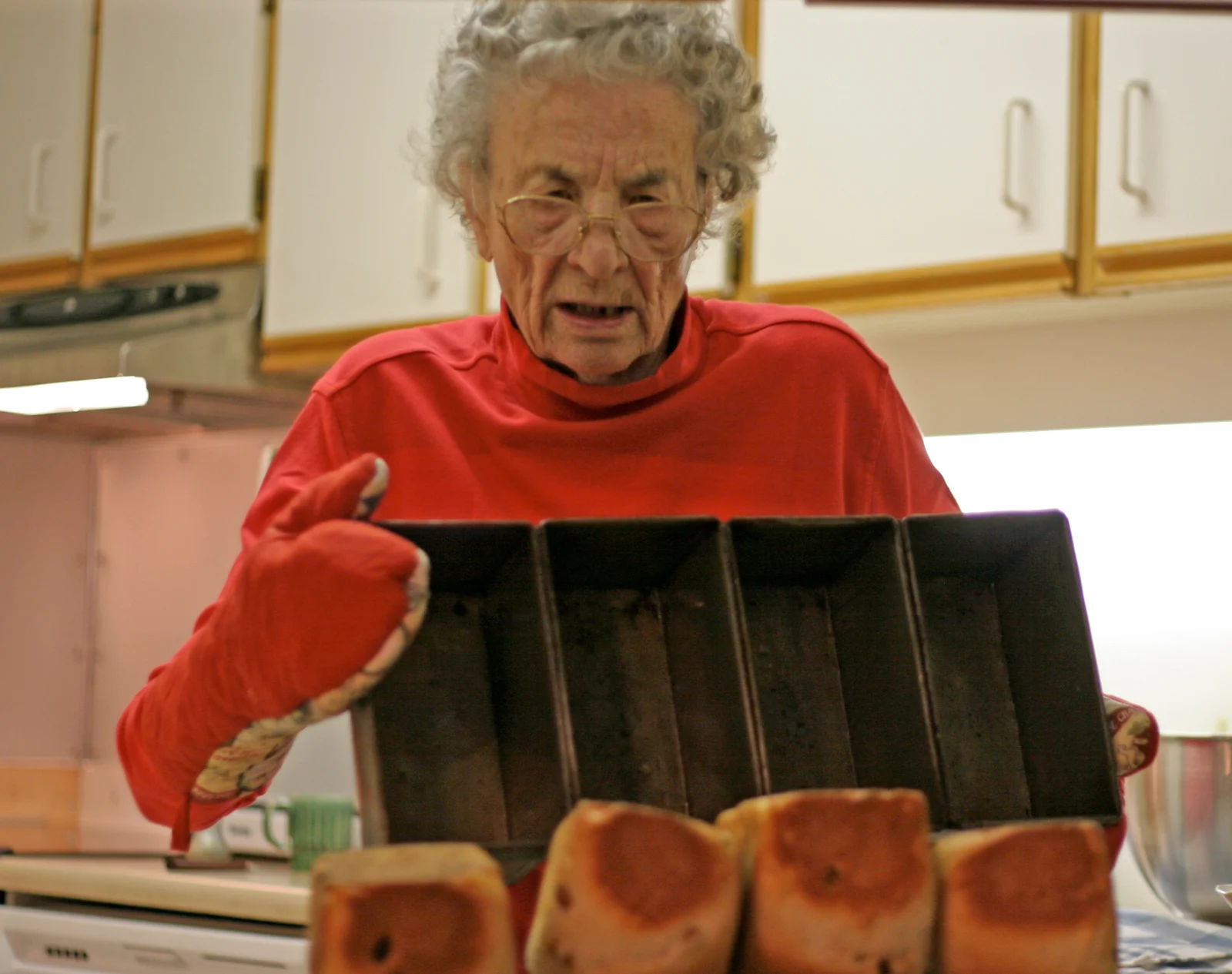 Granny pulling a pan of loaves from the oven
